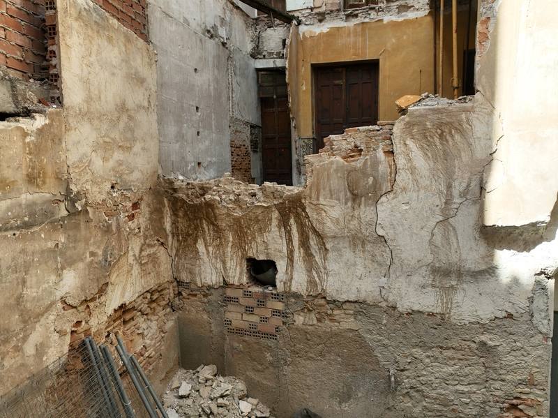 Patio interior de un edificio antiguo con muros agrietados, manchas de humedad y ladrillo a la vista, fotografiado con dron